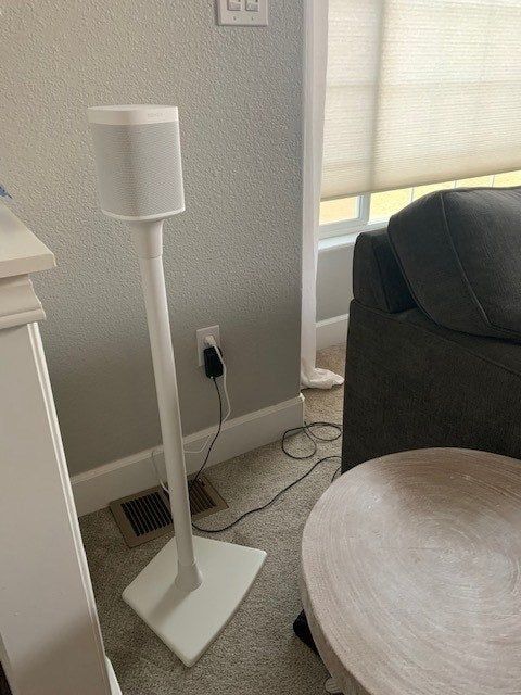 A reviewer's Sonos speaker positioned on a speaker stand, enhancing the room's acoustics.