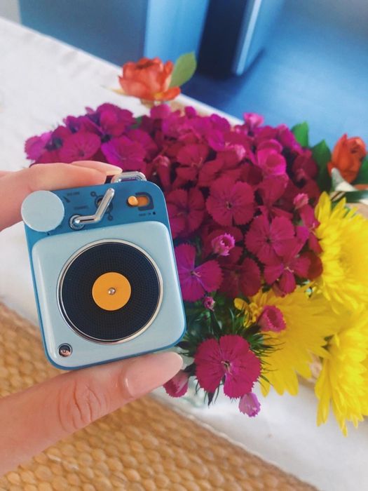 A reviewer holding the blue version of the speaker.