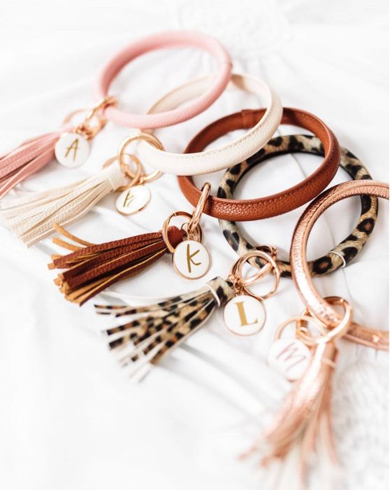 a collection of tassel bracelets with personalized initialed charms