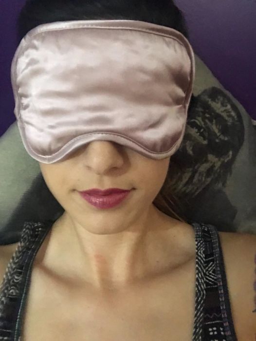 A reviewer wearing the pink sleeping mask