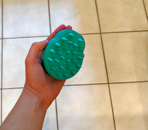 The reviewer highlights the underside of the brush, which features soft rubber spikes designed for gentle use.