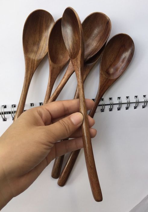 A person holding one of the wooden spoons