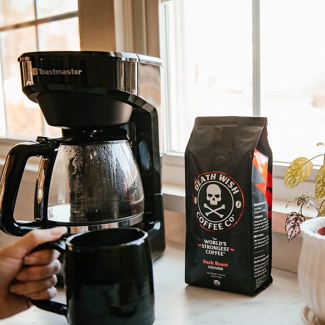 a bag of Death Wish coffee placed next to a coffee maker and mug