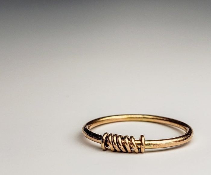 A simple gold band featuring seven small round rings around it