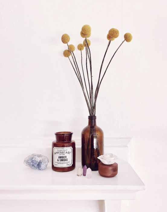 A reviewer’s candle placed beside a matching amber bottle