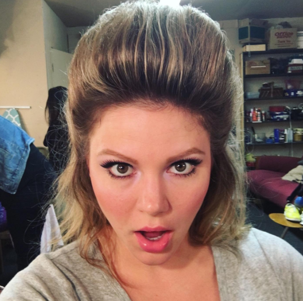 A reviewer sporting a bouffant hairstyle that’s several inches tall