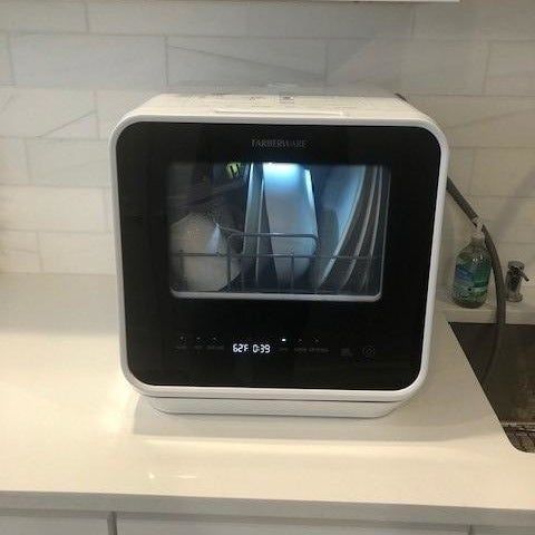 The dishwasher in action with several plates, a shallow bowl, and a mug inside