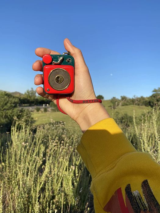 A reviewer holding the red version of the speaker.
