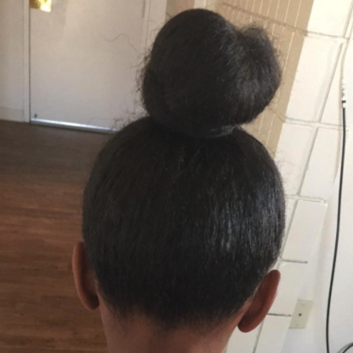 A little girl's hair styled into a sleek, neat bun after being brushed.