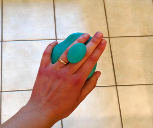 The reviewer demonstrating how the knob of the scalp massager fits comfortably between your fingers for a secure and easy grip.