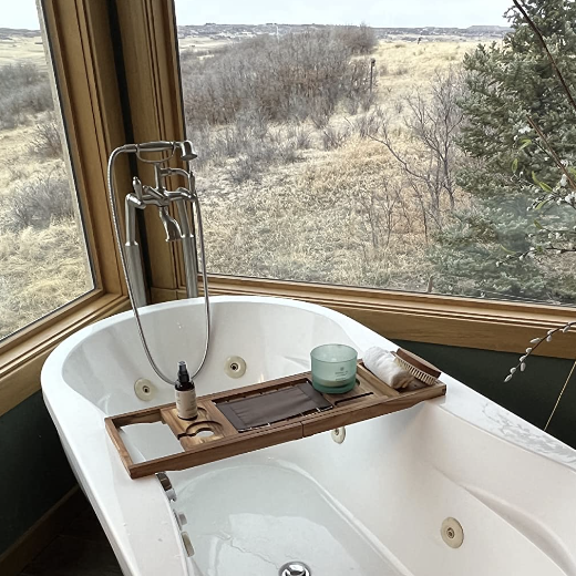 a reviewer's bathtub with windows on either side, showcasing the bath caddy placed on top