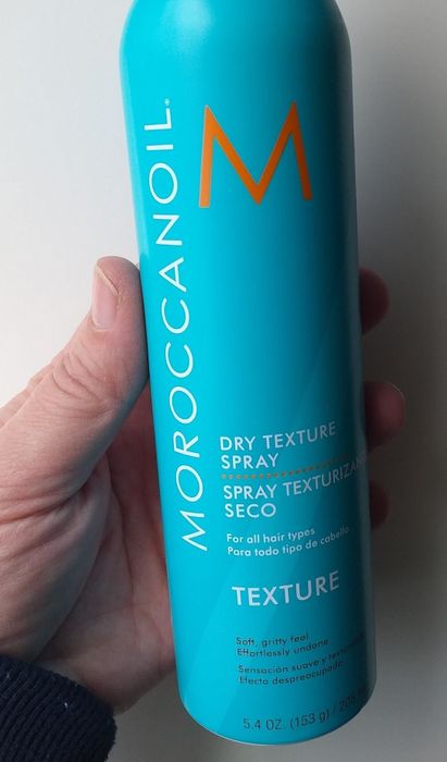 A reviewer holding the Moroccanoil Dry Texture Spray bottle.