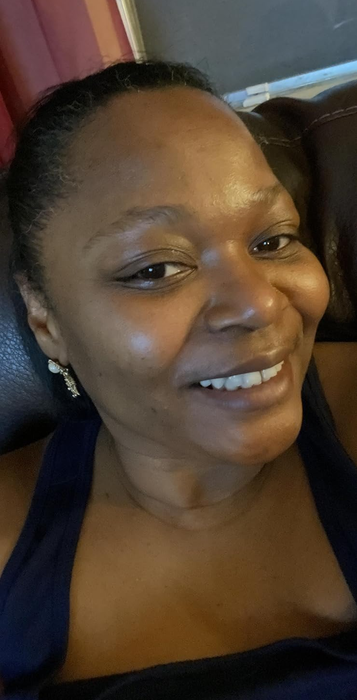 A reviewer smiles at the camera while relaxing on a leather sofa.