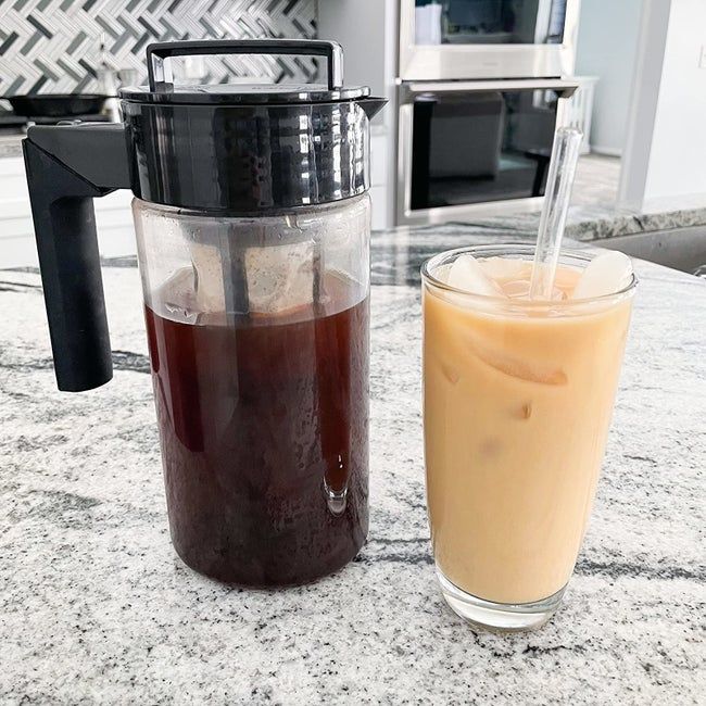 A reviewer shows a full cold brew maker placed beside a glass of iced coffee.
