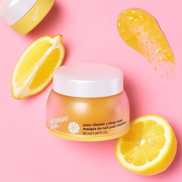 A jar of Yuzu Vitamin C Sleep Mask displayed next to fresh lemons.