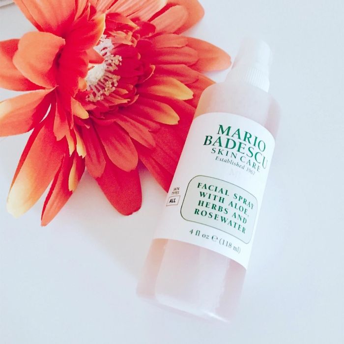 A reviewer's photo showing the facial spray bottle placed next to an orange flower