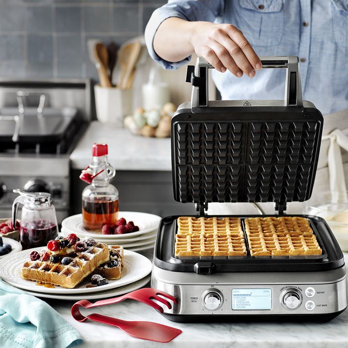 Waffles cooking in an open waffle maker, placed on the kitchen counter.