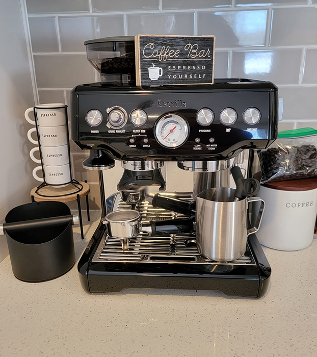 A reviewer proudly displays their sleek black espresso machine sitting on the kitchen counter.