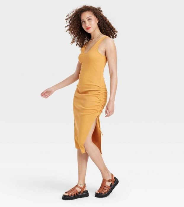 A model showcasing a yellow ruched knit dress, emphasizing its sleek and stylish design.