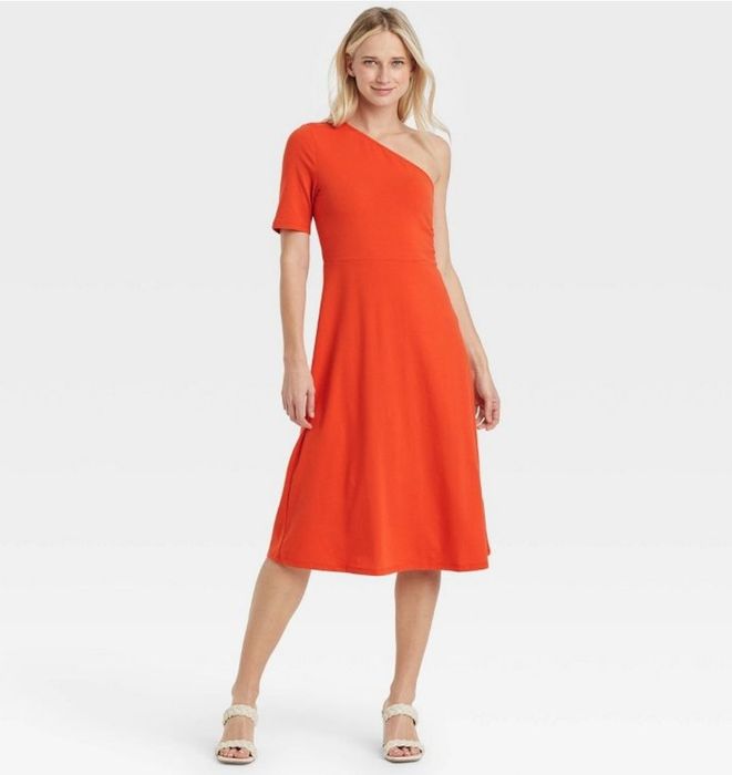 A model is wearing a vibrant red one-shoulder dress.