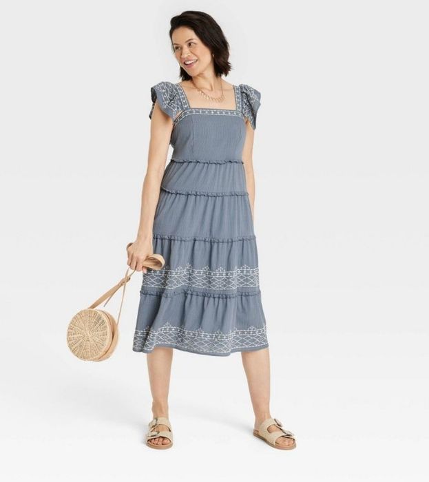 A model in a blue embroidered dress, elegantly showcasing its design.