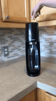 A gif showing a Mytourer using a sleek black SodaStream machine