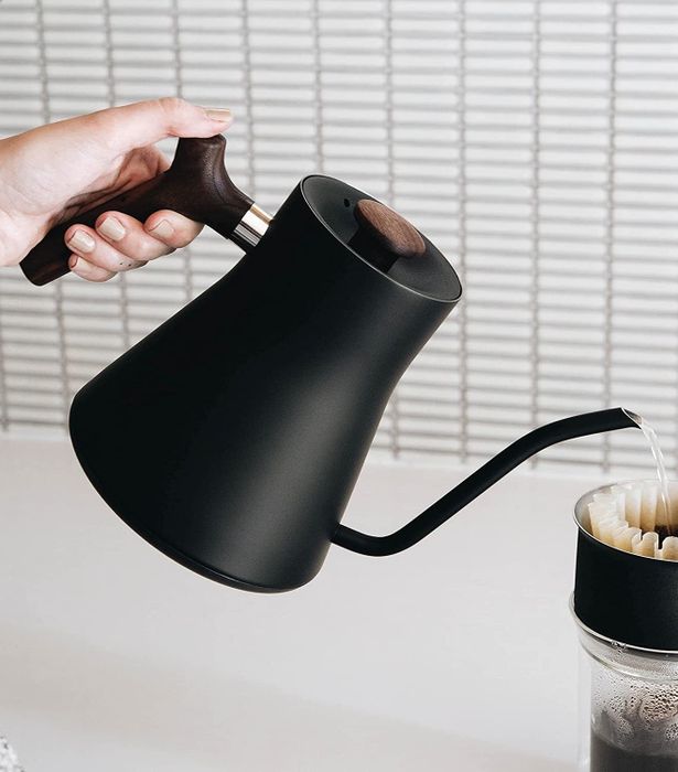 A model pours hot water into a pour-over coffee cup, carefully preparing the perfect brew.