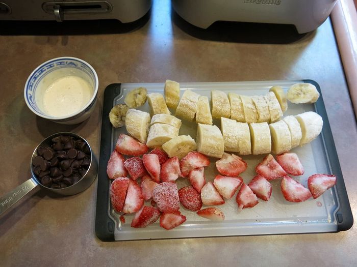 Sliced frozen fruit on a cutting board, ready for making soft serve.