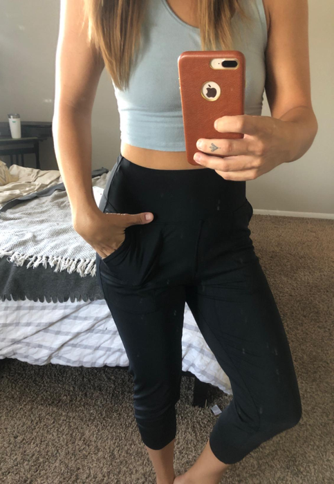 A reviewer displays the front view of the black joggers.