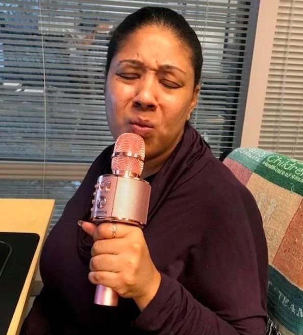A reviewer singing with the pink karaoke microphone