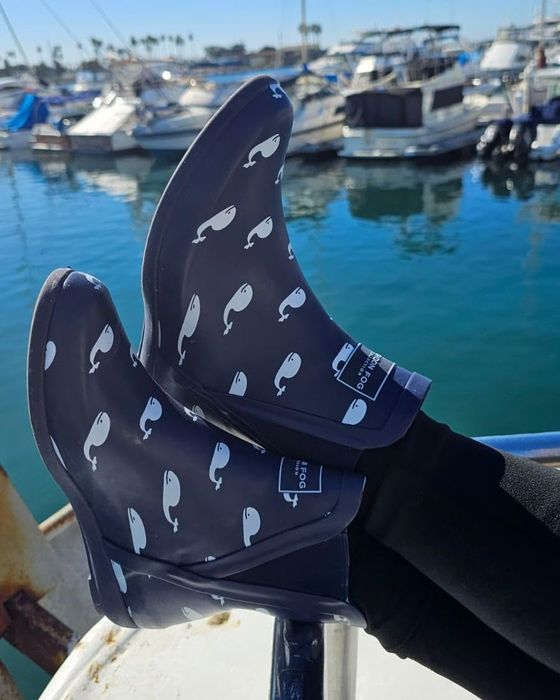 The reviewer is wearing blue rain boots decorated with whales on them