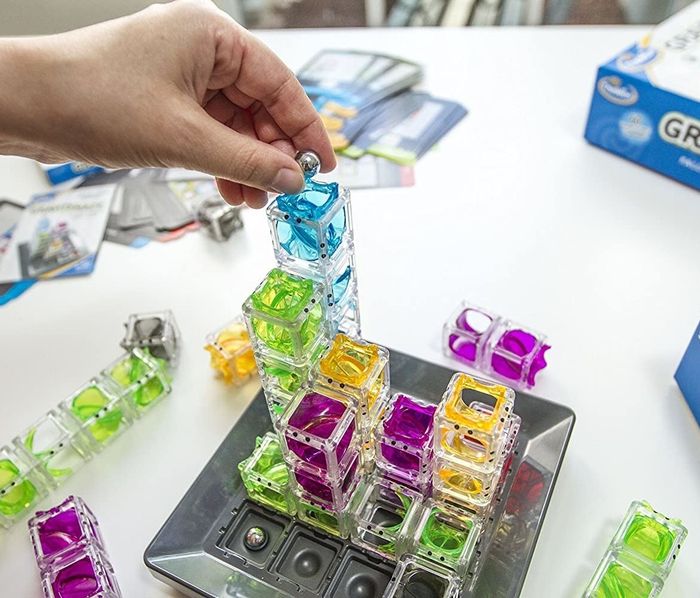 A model placing a marble at the top of the clear stacked cubes on the Gravity Maze game board
