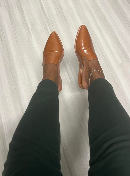 Individual wearing dark tan leather mules