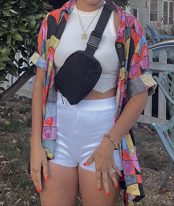 A reviewer is seen wearing the fanny pack styled across the body for a hands-free, practical look.