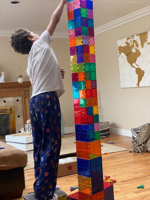 A reviewer’s photo of a child constructing a tower taller than they are using the magnetic tiles