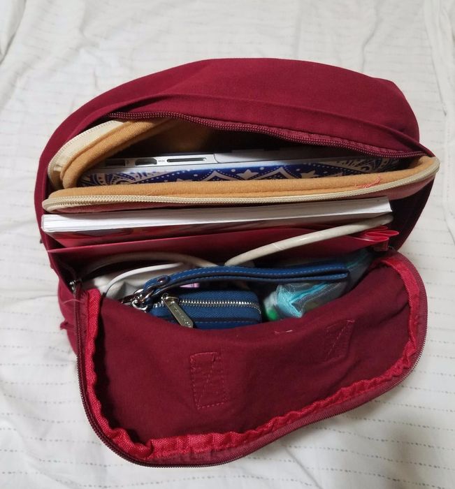 A close-up of the inside of the canvas backpack, showing its contents including a laptop, wallet, and book.