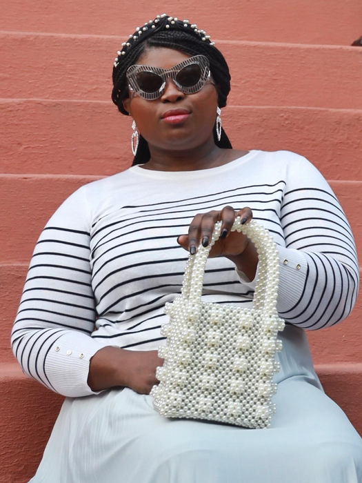 A reviewer is seen holding the cream-colored beaded handbag.