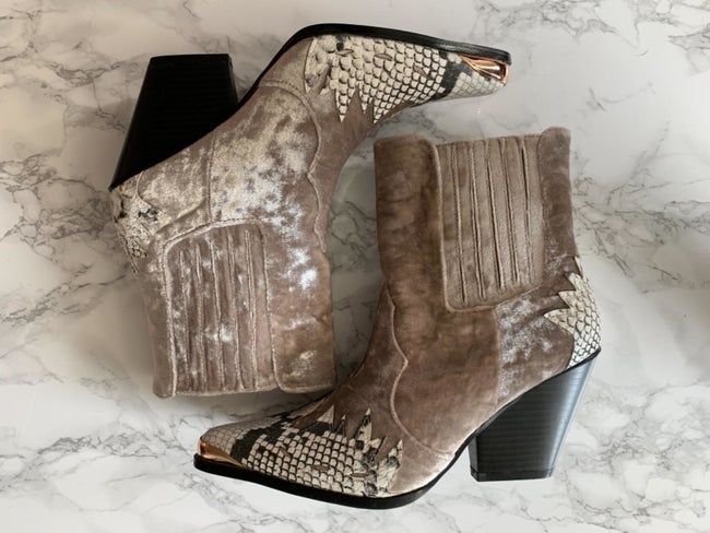 The mixed media boots feature taupe-colored velvet with snakeskin accents and a black heel.