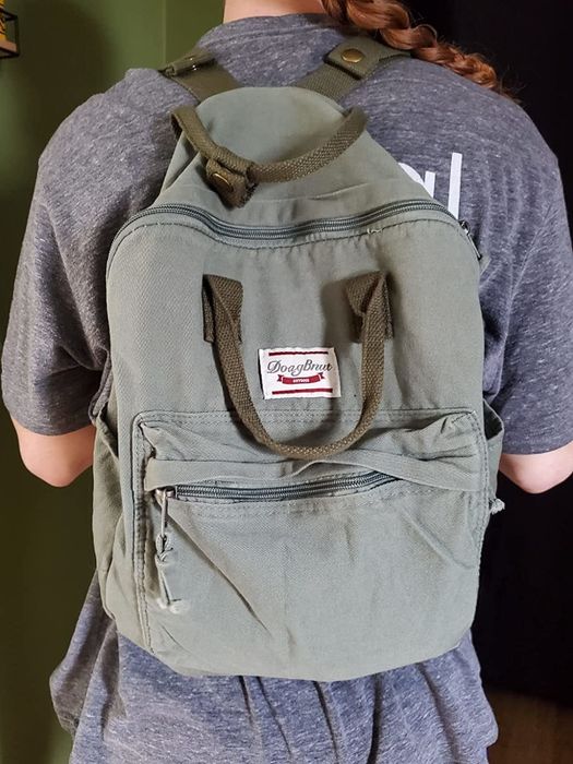 A reviewer models the army green backpack.