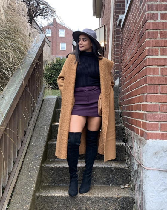 The reviewer is sporting black boots paired with a mini skirt.