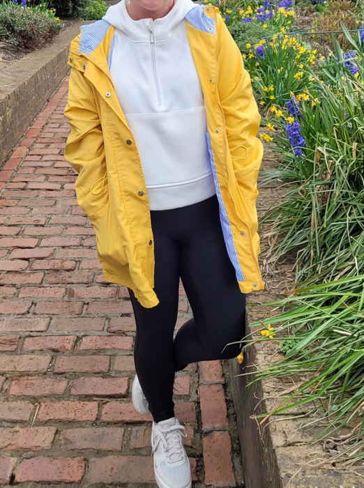 A reviewer wears the white pullover under a yellow raincoat.
