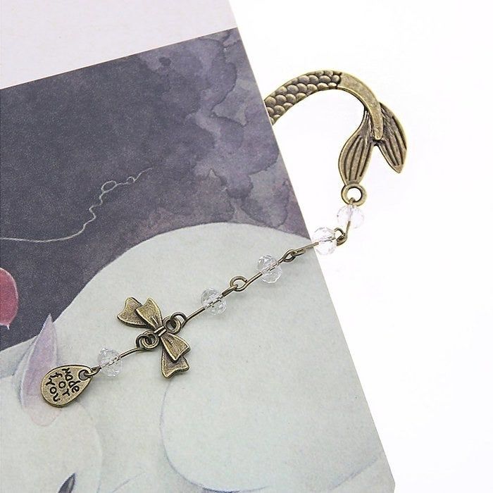 the mermaid's tail peeking out from a book with beads hanging from it