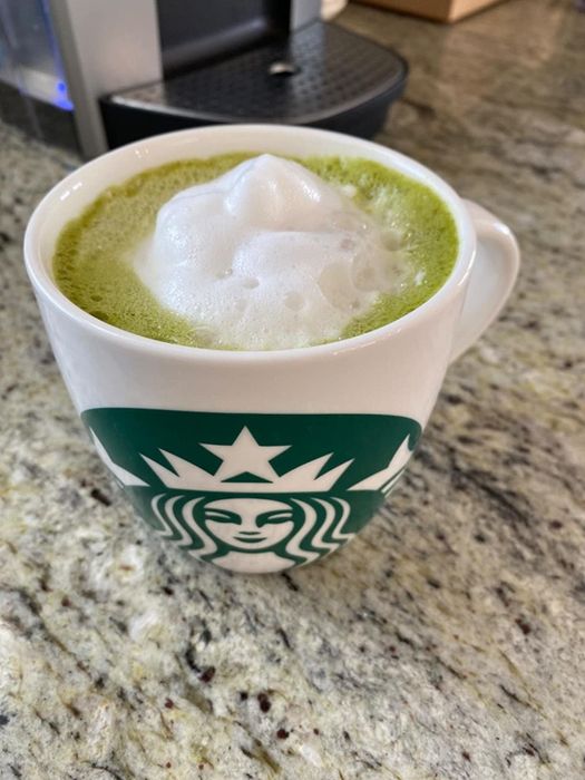 Reviewer enjoying a cup of coffee topped with a fluffy layer of foam.