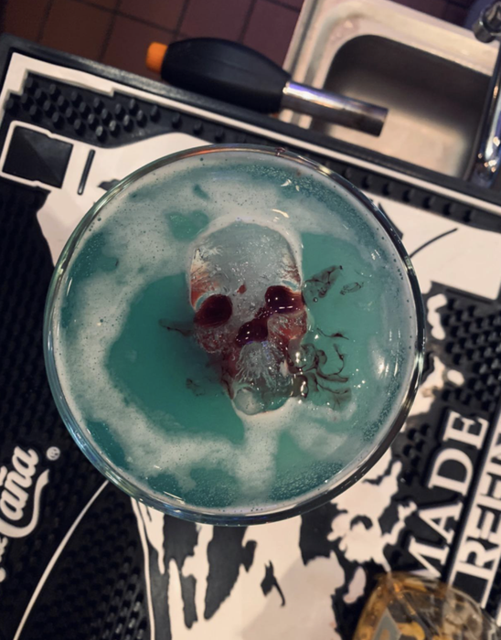 Reviewer image showing a skull-shaped ice cube partially submerged in a frothy blue cocktail.