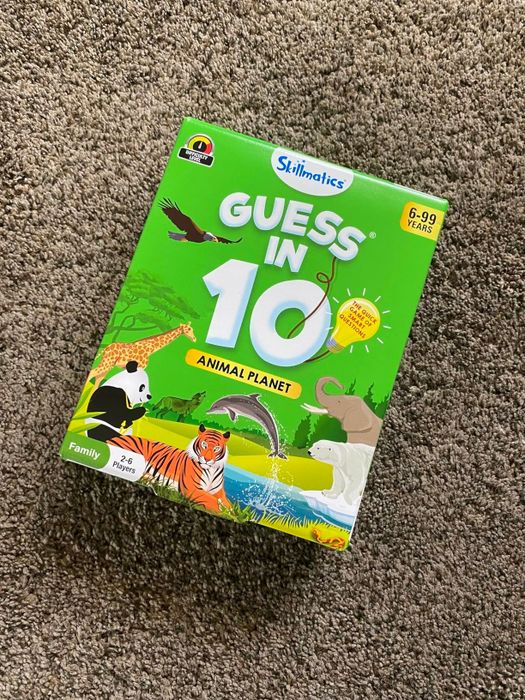 The Guess in 10: Animal Planet game box resting on a carpet. Includes animals like tigers and pandas, suitable for ages 6-99, and playable by 2-6 players.