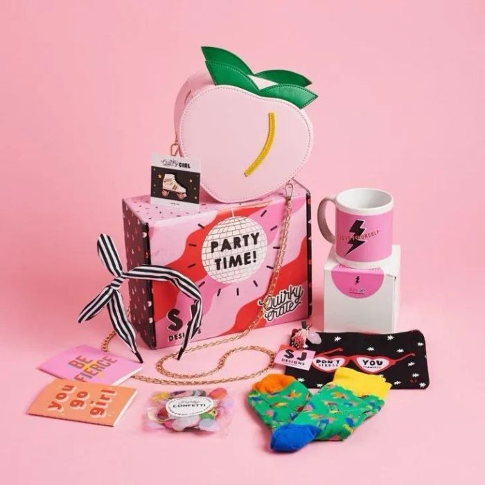 A pink box filled with socks, a mug, a peach-shaped purse, and other vibrant items.