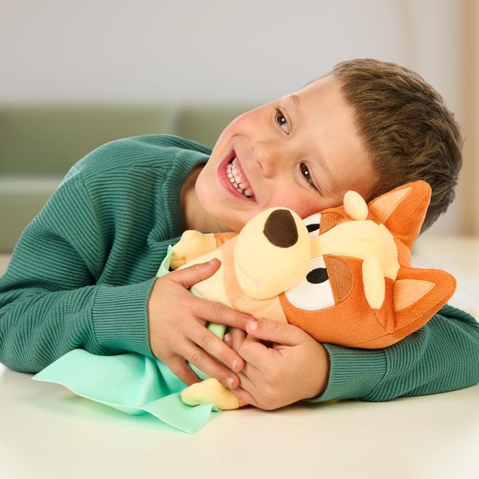 A child joyfully hugging a plush toy while lying on a table, featured in a shopping article.
