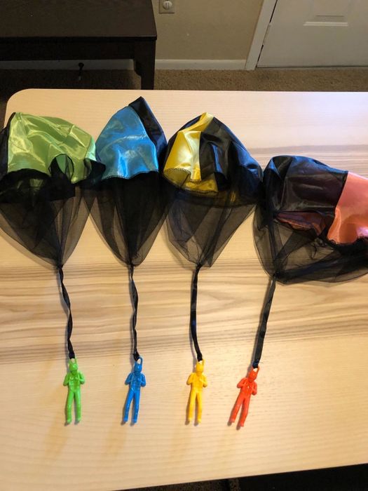 Toy parachutes in green, blue, yellow, and red, scattered across a table, ready for play