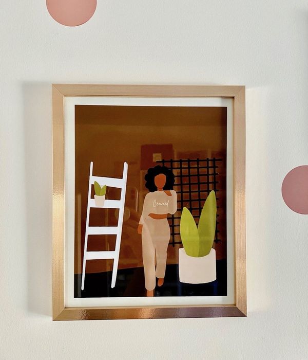 A framed print of an illustrated Black woman wearing a sweatshirt that says