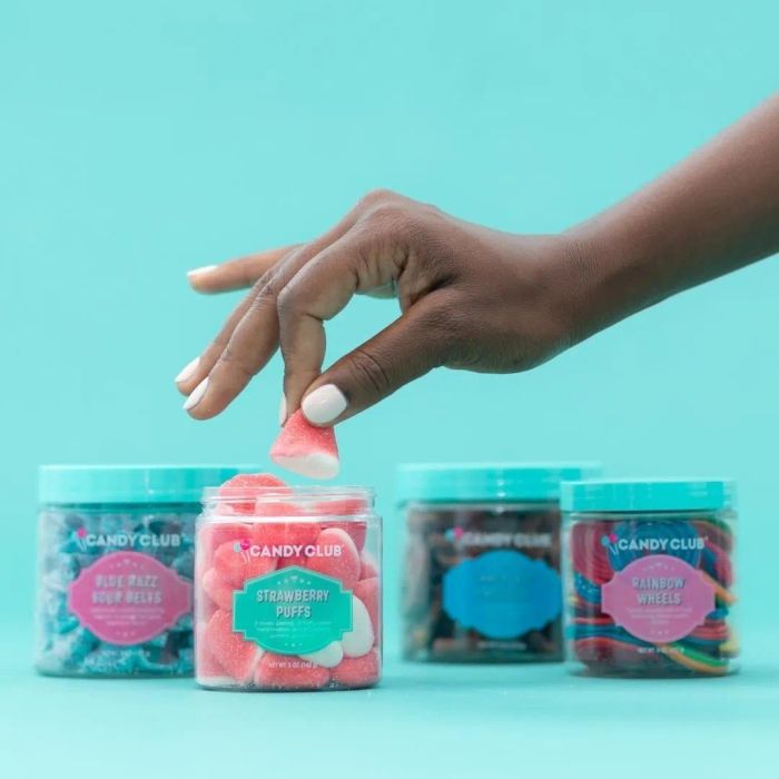 Four jars filled with a variety of candy: rainbow wheels, strawberry puffs, blue raspberry sour tape, and a delightful chocolate treat.